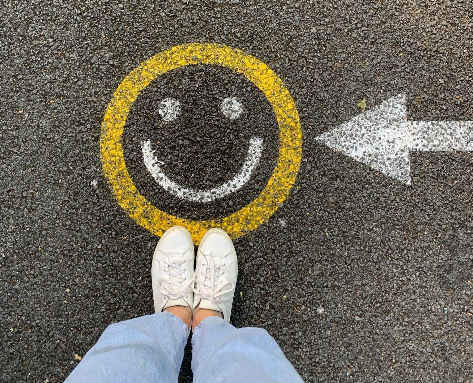 Girl standing on painted yellow smiley face with arrow pointing to the smiley face