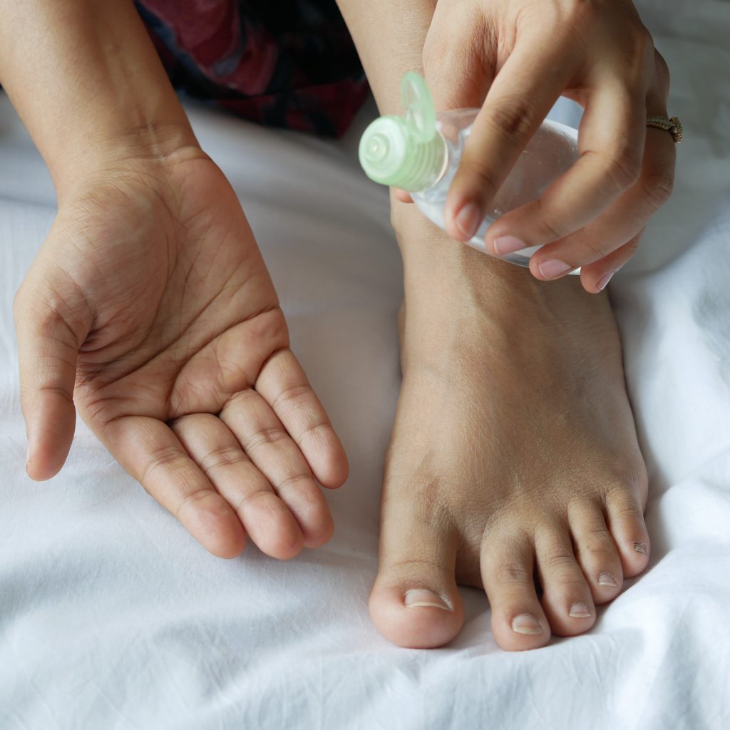 Woman holding massage oil beside foot